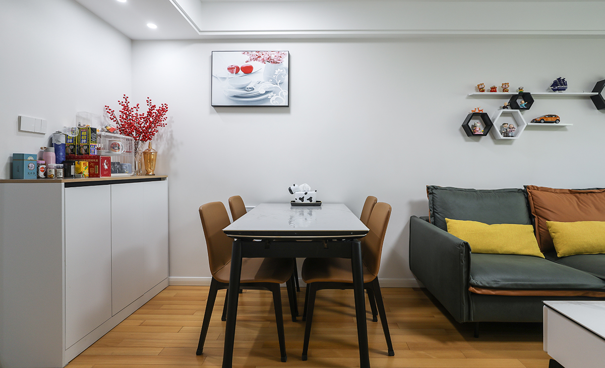 餐廳餐桌搭配餐邊柜，既實用、又有裝飾功能，頂上筒燈增加氛圍感，墻面一幅裝飾畫把餐廳點綴的很有生機，巖板餐桌把用餐硬度高又好打理，放油抗污，地面同客廳地板通鋪，整體色彩和造型上都簡潔大氣。