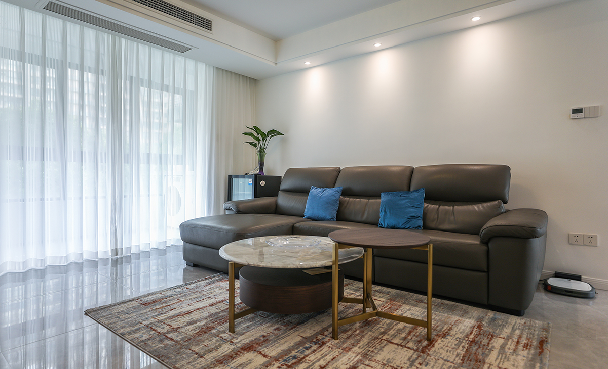 沙發(fā)背景刷米灰色涂料，白色的沙簾，沙發(fā)背景留白設(shè)計(jì)，色調(diào)上墻面涂料和窗簾用淺色，沙發(fā)用深色，深淺搭配的錯(cuò)落有致，既溫馨又簡(jiǎn)潔。
