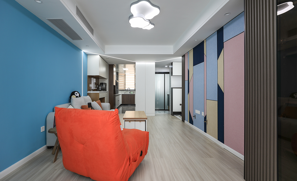 客廳是男主活動頻率最高的區域，要求寬闊、明亮。電視墻采用色彩明亮的幾何墻布，淺灰色皮質沙發配木色方型茶幾加上淺木色復合地板，造型和色調上無不給人以簡潔、大氣、時尚的感覺。