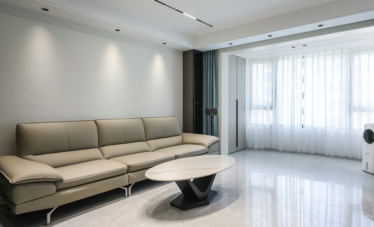 巖板臺面的茶幾襯托出時尚的質(zhì)感，射燈加上頂面的磁吸軌道燈投射出不同范圍的光源，沙發(fā)旁的玻璃柜時尚大氣，典雅的顏色與灰色墻面相得益彰，更與沙發(fā)形成落差，極具設(shè)計感和居家體驗感。