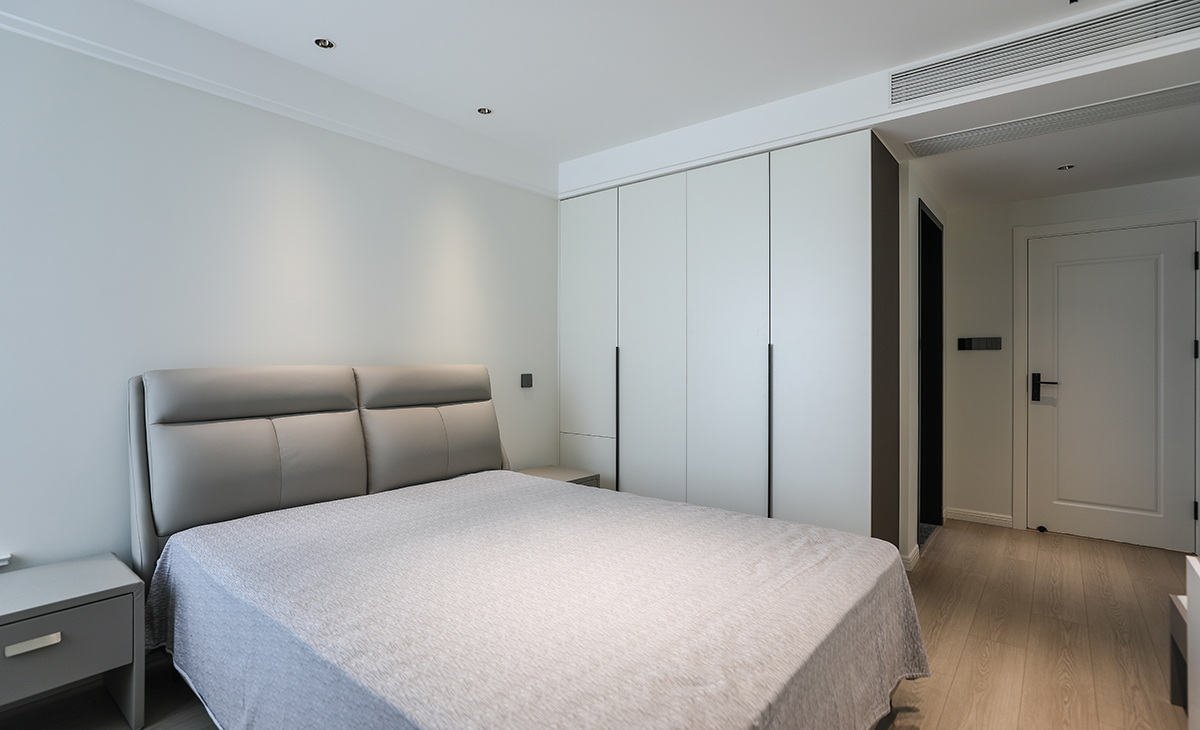 主臥地面鋪以暖灰色地板，衣柜與墻面色彩統(tǒng)一，相得益彰。四周雙眼皮吊頂加上中間拉平無主燈的設(shè)計，讓空間顯得尤為寬敞，灰色的床及床頭柜與整個風格進行搭配，渾然一體，整體協(xié)調(diào)，盡顯主人高端品味。