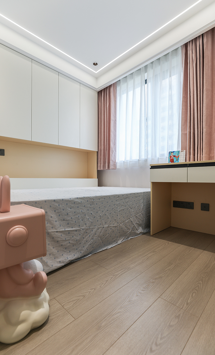 女孩房的色彩相對偏暖，通過改變軟裝的搭配，選擇粉紅窗簾和粉色床頭柜，讓整個空間顯得溫馨浪漫。淡妝濃墨總相宜，色調(diào)的改變更加讓主人的小女兒充滿向往，圓了小女孩的一個新居夢。