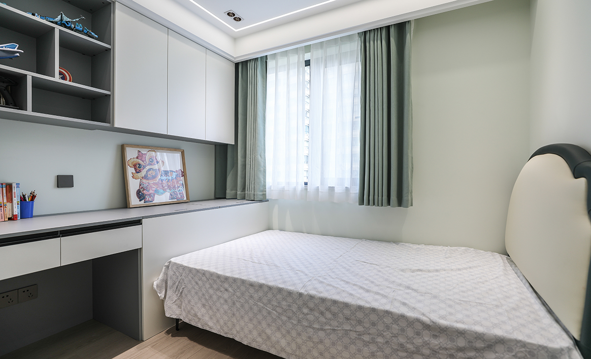  男孩房的頂面不再是傳統(tǒng)的一個主燈，而是改為一圈線燈和筒燈的結(jié)合，打破傳統(tǒng)，突破局限，營造了一個明亮且線條感更強的氛圍，床尾的定制吊柜和寫字桌，上下對應(yīng)，給孩子創(chuàng)造了一個獨立的學習和娛樂空間。