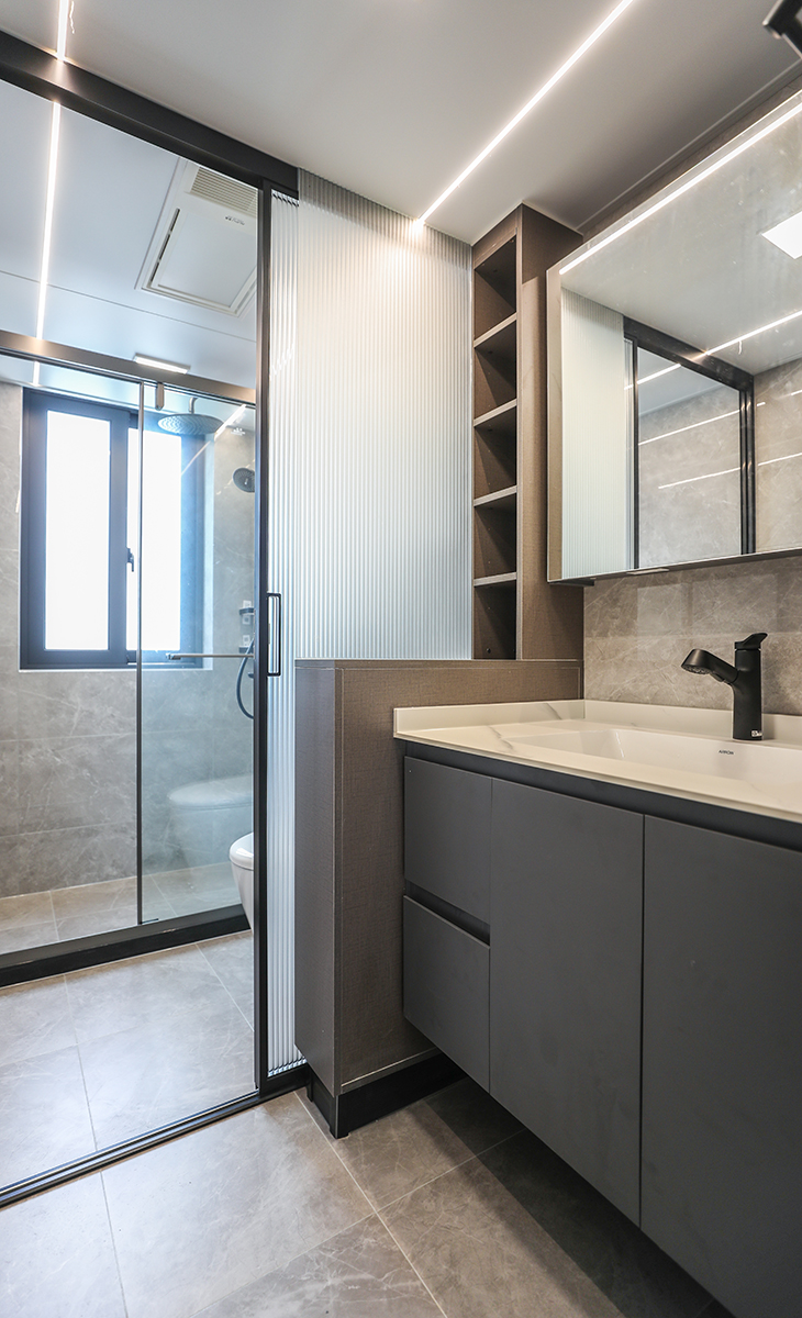 位于通道上的客衛(wèi)生間，采用了干濕分離的設(shè)計，將空間合理劃分。通過防水柜體與長虹玻璃組合來進行隔斷，增加收納的同時也將空間延伸，吊頂采用小方燈加線燈的組合，更具線條美。