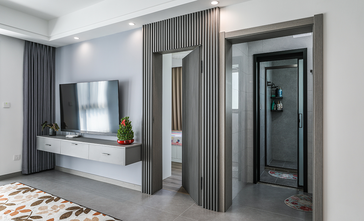 電視墻做隱形門設計，通過格柵將房間門和電視墻做到渾然一體。