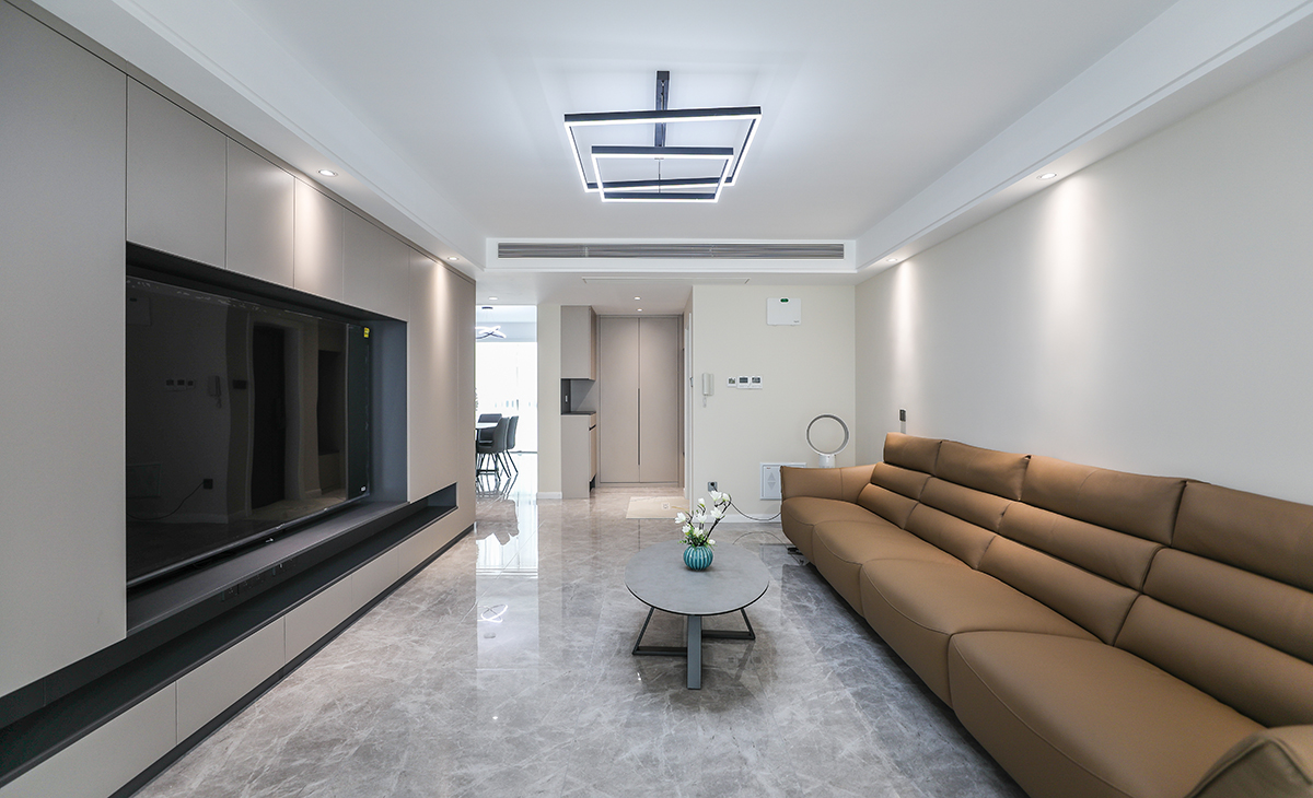 客廳開間很大，滿面電視柜非但沒有讓空間顯得壓抑，反而看起來很大氣，門口的組合柜，沒有因為都是柜子顯得單調，反而又一次拉長了空間，公共區域滿鋪750*1500的大磚，縫隙更少，整套裝修都以簡潔的線條為主，不過多修飾，反而還原了裝修本身的意義，舒適，減少衛生死角，滿足一家人多口所有儲物需求。