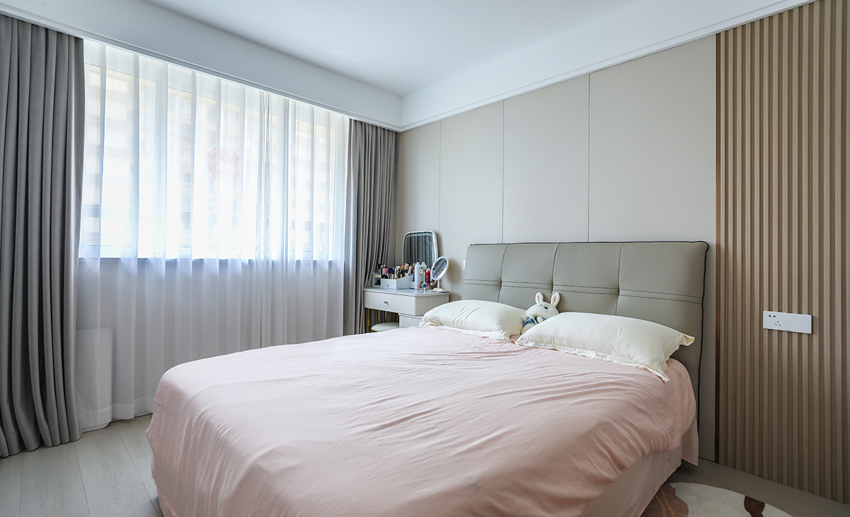 主臥床頭背景和客廳沙發背景一樣采用了同材質來裝飾，做到了統一風格以及色系。地板選用淺色系的灰木紋地板，再配上同色系的床來搭配。讓整個空間顯得干凈簡潔。