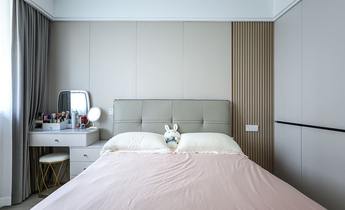 主臥床頭背景和客廳沙發背景一樣采用了同材質來裝飾，做到了統一風格以及色系。地板選用淺色系的灰木紋地板，再配上同色系的床來搭配。讓整個空間顯得干凈簡潔。