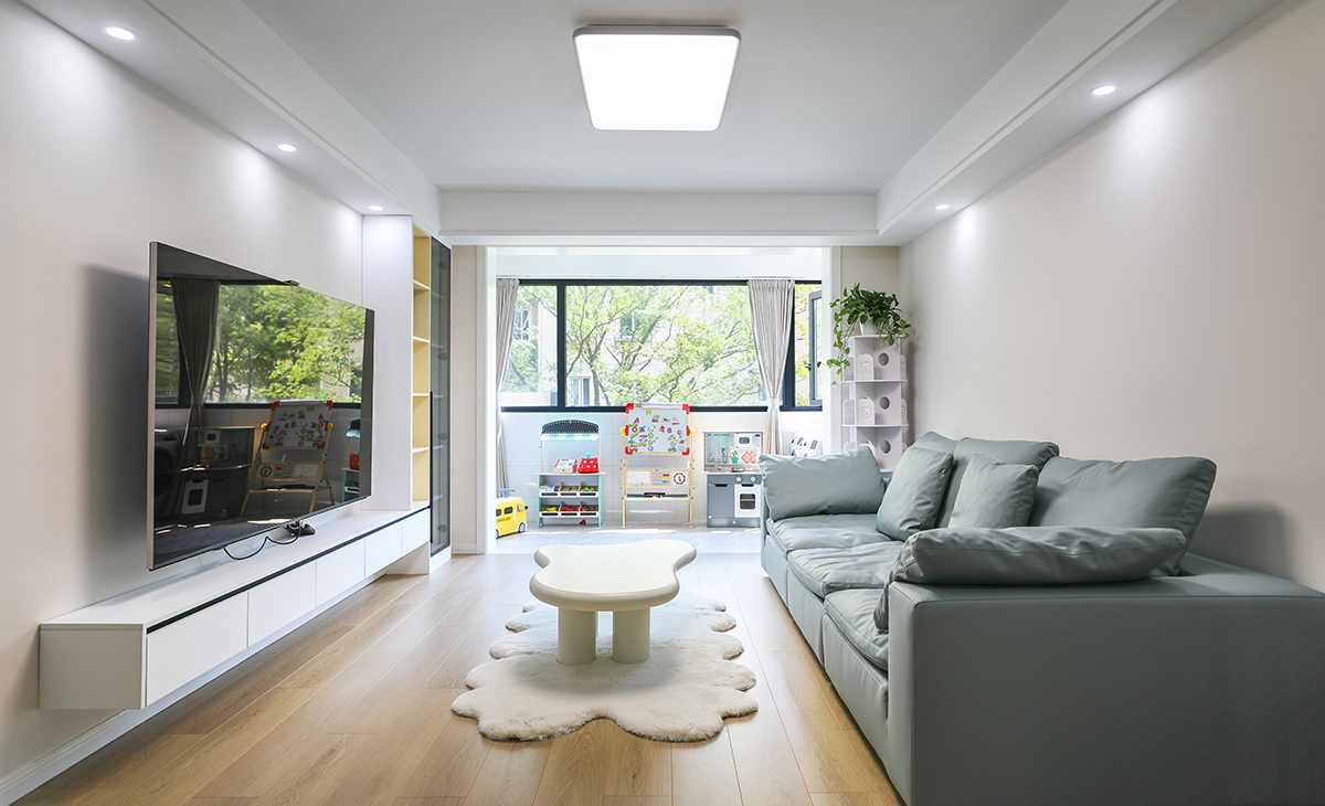 客廳的色彩搭配為墻淺地深的配色理念，這樣對于整體性有不可忽視的效果，沙發的背面做了木格柵裝飾，讓原本單調的墻面有了生機。