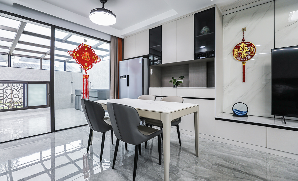 餐廳空間比較方正寬敞，又有一個大落地窗，靠墻做一排裝飾柜，既實用、又有裝飾功能，膚感灰+木色框架，極窄邊框玻璃門門板相呼應，巖板餐桌把用餐氛圍調和的很溫暖，淺灰色地磚很干凈，色彩和造型上都簡潔大氣。