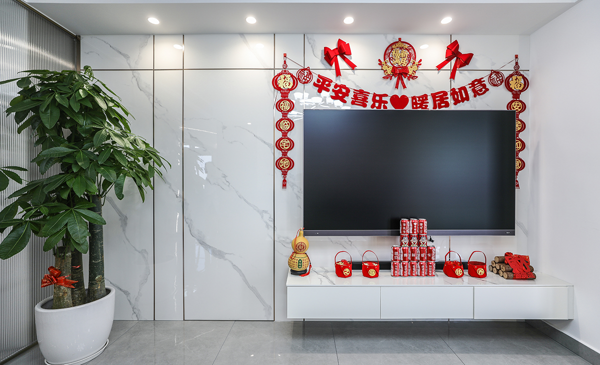 亮光石紋竹木纖維板和極窄線條將房門和背景完美集合，電視柜左邊的裝飾盆景作襯托，巖板臺面電視柜也很大氣，讓空間不但時尚而且清爽。