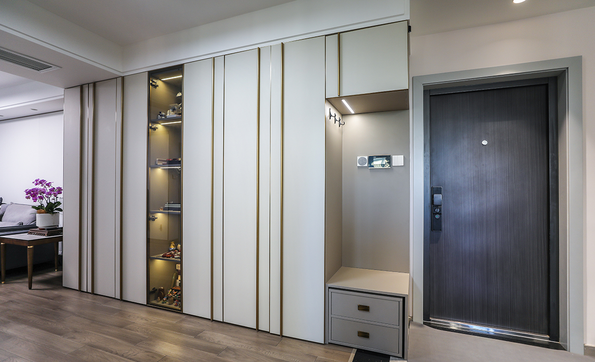 進(jìn)門玄關(guān)處，做了一大排儲藏柜，解決了家中收納少的問題，因?yàn)樵诠矃^(qū)域，為了使整個柜子不那么沉悶，中間加了玻璃門，里面放上展示品，整個空間的格調(diào)一下就上去了。