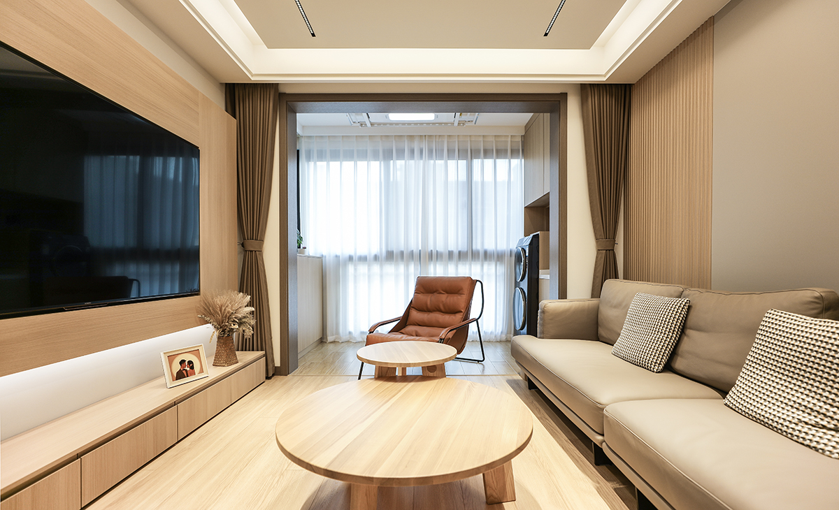 客廳長方形戶型，電視墻以原木色板材凸出來，把電視機嵌入形成一個完成面，底部做線性燈，很有氛圍感，底部用白色涂料更能凸顯整體效果圖。沙發背景墻左邊以現代流行的格柵為主，右邊墻同樣采用咖啡色木飾面相結合，沙發背景墻和電視劇背景墻同樣用兩種顏色和不同造型相結合，茶幾選的配套原木色餐桌，圓形大小相結合，再配個咖啡休閑凳子，舒適而愜意。吊頂采用現在很流行的線性無主燈。地面采用原木色地板。整體空間既突出來時尚、簡單、大氣、溫馨的感覺。