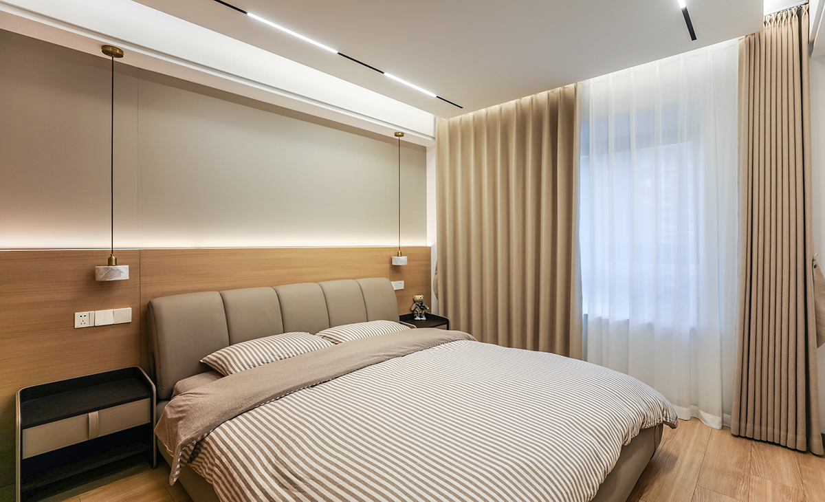 主臥地面鋪的實木復合地板，背景墻選了現在比較流行的硬包+原木色墻板，柔和的色調，半墻造型點綴燈帶線，讓家里氛圍感更純粹。皮革硬包+原木色木飾面+燈帶，見光不見燈，美觀又大方。頂上采用懸浮無主燈+線性燈，配上兩邊的吊燈，整個空間層次明細，整體效果突出，配上咖啡色的窗簾和白沙，更大氣，時尚。