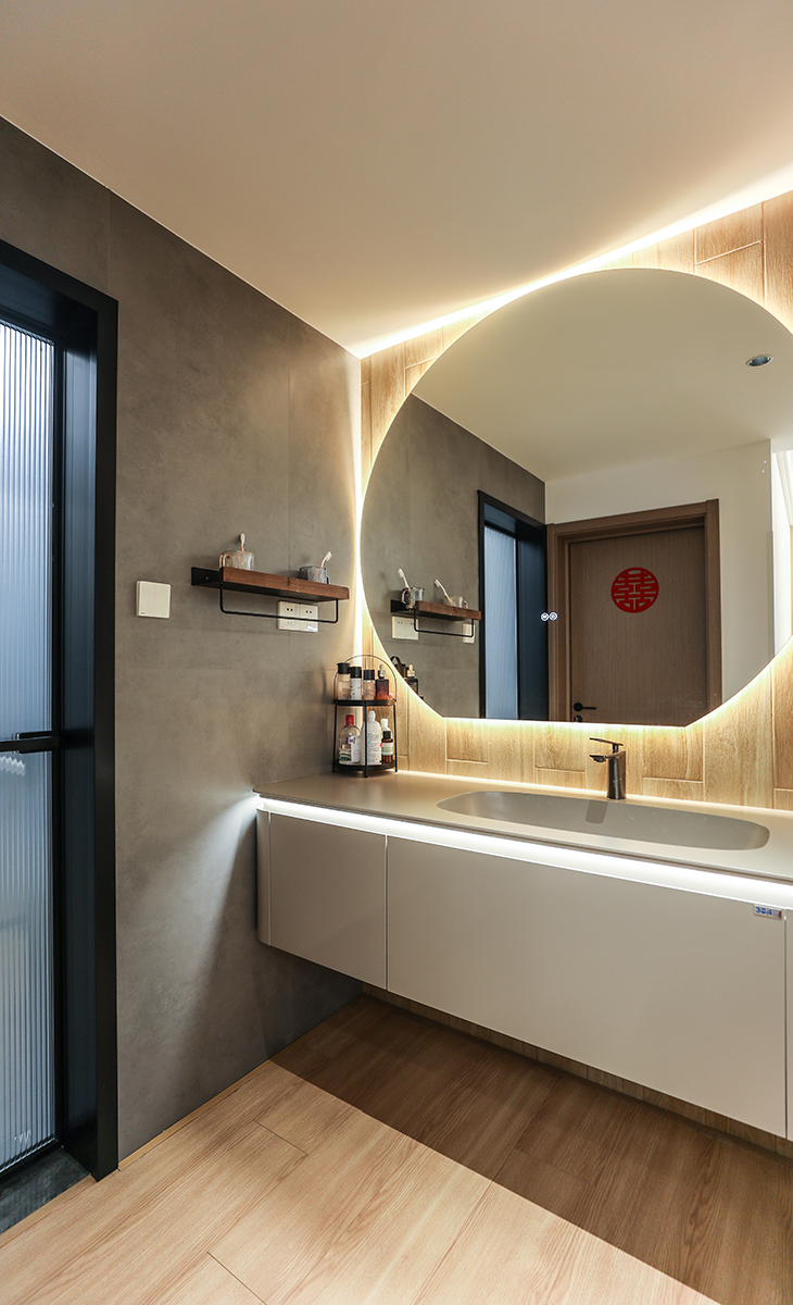 衛生間地面鋪600*1200的啞光灰色地磚，直接拿地面磚上墻，整個空間更大氣、明亮，衛生間濕區采用木紋磚，更干區的臺盆柜墻面顏色統一，地面選用的槍灰色地漏，頂面采用現在流行的蜂窩大板，再配上線性燈和筒燈，讓整個衛生間更上檔次和溫馨。淋浴龍頭的位置，做了一個壁龕，分三層，可以平時作為收納功能使用，淋浴房、淋浴龍頭、地漏全部選擇一個顏色，整個顏色統一，更能凸顯原木風。