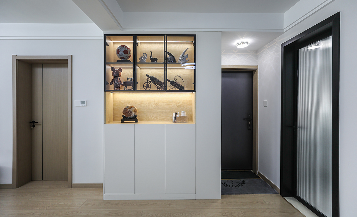 廳空間比較方正寬敞，靠墻做一排裝飾柜，既實用、又有裝飾功能，原木色框架，極窄邊框玻璃門和白色木門板相呼應，巖板餐桌臺面把用餐氛圍調和的很溫暖，原木色地板很干凈，色彩和造型上都簡潔大氣。