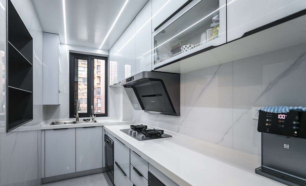 廚房的空間不是很大，做了L型櫥柜，在墻面上做了一個壁龕，增加儲物空間。顏色簡潔明快，材質要干凈和好打理，白色的吊頂和米色的上櫥柜、深色的下櫥柜相呼應，石英石臺面干凈、好打理，各種廚房電器全部配齊，滿足主人制作各種美食的需求。