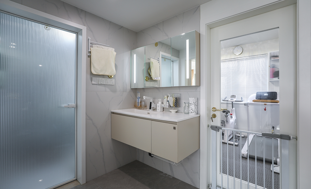 衛(wèi)生間做干濕分開，淋浴區(qū)利于原有管道做壁龕增加儲物的同時合理利用每一份空間，馬桶上增加儲物柜，增加收納空間，金色窄框淋浴房，線條簡單，墻地面通鋪一體大磚，單獨淋浴區(qū)同色小磚做下水坡度。讓整個空間協(xié)調(diào)統(tǒng)一，大氣時尚