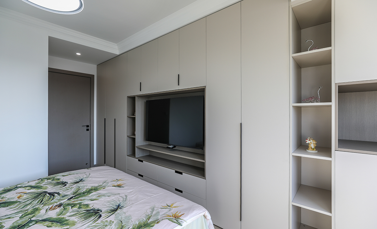 主臥采用一排大衣柜，增加儲物空間，地板也是淺灰色和衣帽柜進行搭配，讓空間色調融為一個整體，頂面一圈石膏線以簡潔平板為主，方便打理，體現了簡約風格的簡潔、隨意，不拘一格。