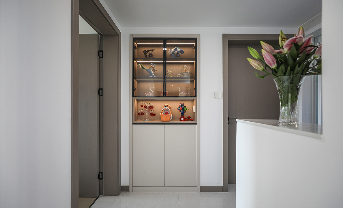  本套房子的走道儲物柜設計也是一大亮點，既實用，又有裝飾性，做玻璃門板，加燈帶設計，展示主人收藏的藝術品，和臥室門顏色相統一，給人感覺不僅雅致而且有韻味。