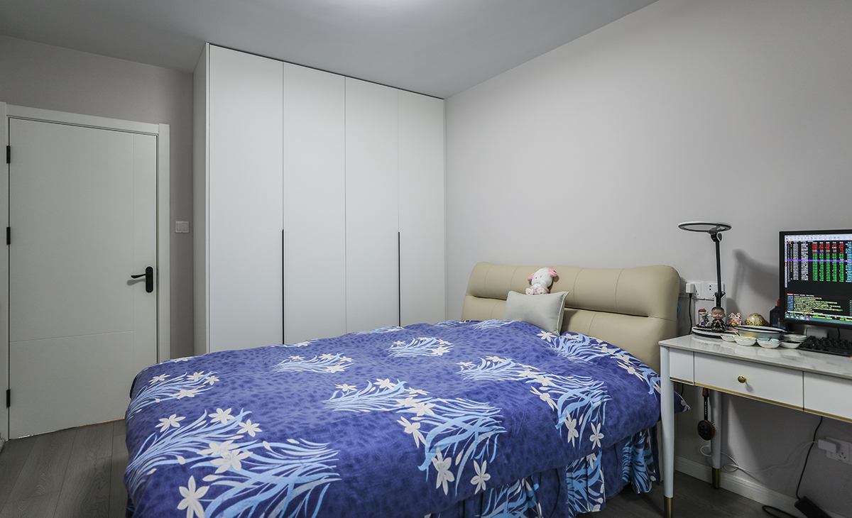 主臥地板為中性色，顏色不灰也不暖，所以床選擇的是奶油色，衣柜門板也是白色，這樣和原來的實木地板進行搭配，就不會那么突兀。白色的書桌白色的木門使整個空間更加時尚、簡約。墻面的涂料材料選用環保、無甲醛的多樂士優質，以保證家居環境的健康與安全。