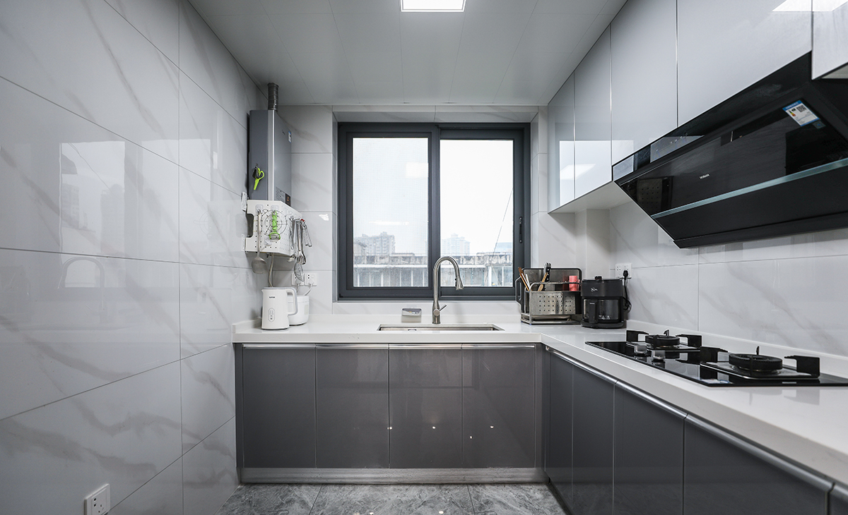 此廚房室L型設計，水槽、切菜，烹飪、等都沿著一條直線或直角排列，這樣的布局既方便了操作，也節省了空間。另外，窗戶的大小也很合理，既保證采光，在視覺感受上也不突兀。色調以黑白為主，線條簡潔，沒有過多的裝飾，看起來非常干凈利落這樣的布局既實用又美觀。
