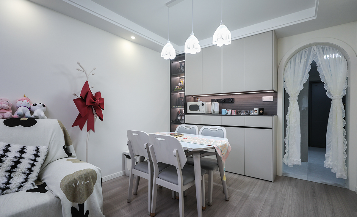 餐廳餐桌搭配餐邊柜，既實用、又有裝飾功能，頂上小吊燈增加氛圍感，玻璃柜和鏤空柜放置燈帶，使空間更加飽滿，巖板餐桌把用餐硬度高又好打理，放油抗污，地面同客廳地板通鋪，整體色彩和造型上都簡潔大氣。