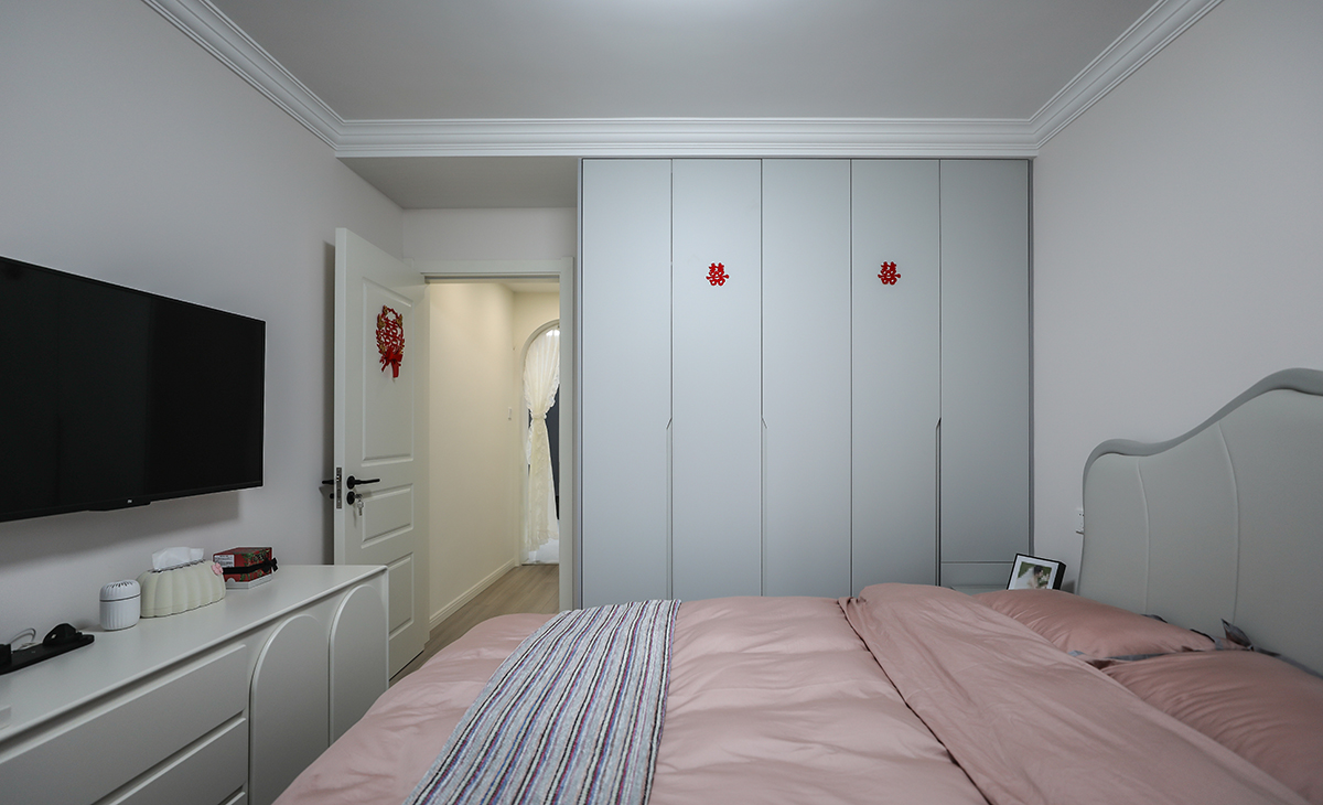 主臥做了到頂的衣柜，增加儲藏，既美觀又實用，顏色上深淺搭配地錯落有致，淺灰木色地板，墻面暖白色干凈清爽，頂面白色乳膠漆，輕巧時尚的吸頂燈，空間很溫馨和諧。