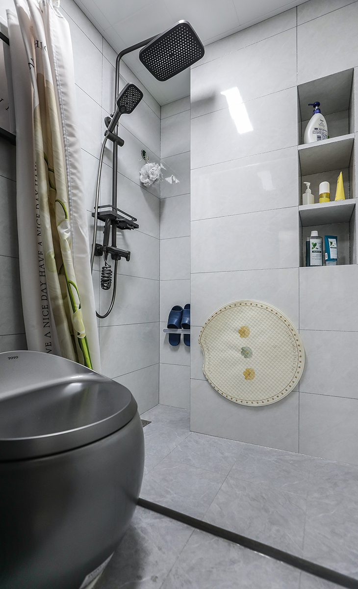 衛生間空間不是很大，彩用干濕分離做法，可以滿足干濕區同時使用，而不影響到對方，地面淺灰色地磚，白色吊頂，鈦合金移門，配上智能馬桶和電熱毛巾架，更加合理的衛浴空間。