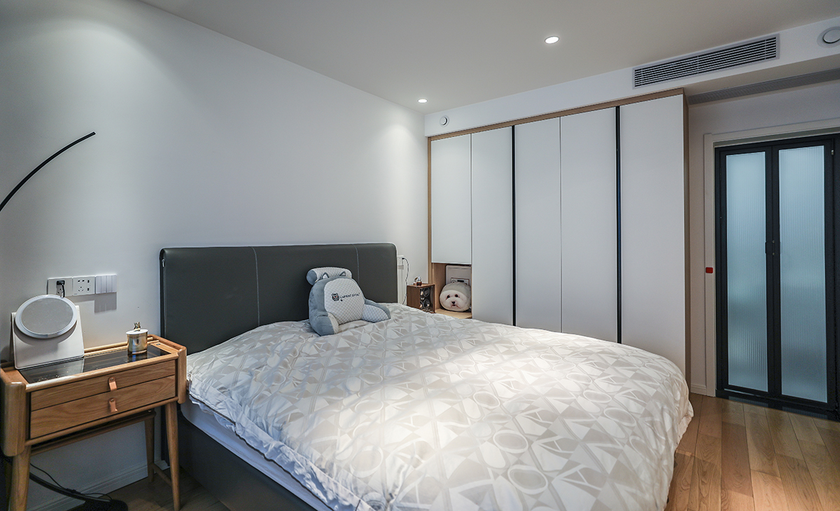 主臥也是無主燈的設(shè)計，主打就是簡潔，地面原木地板，床選擇了灰色的皮床，簡單的原木床頭柜，空間非常溫馨。