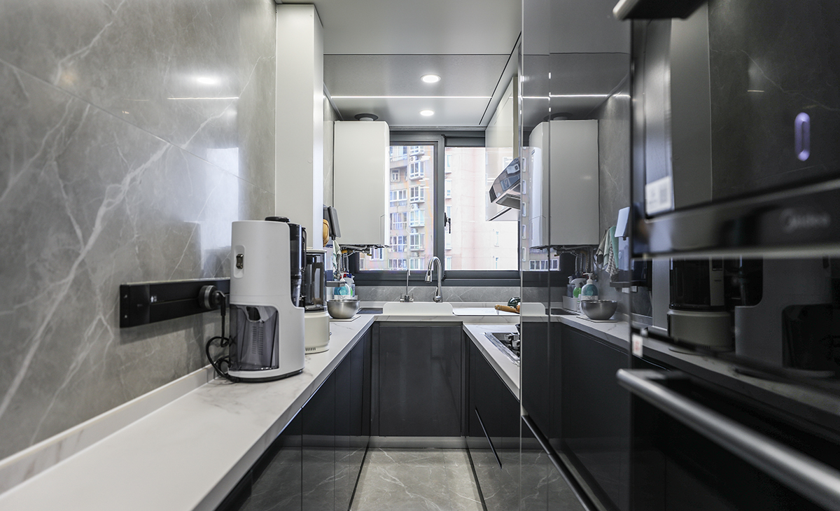 廚房間整體空間不大，業(yè)主對操作臺面要求很高，因此兩面都進(jìn)行了利用，上下櫥柜也選用了上白下灰的拼色處理，空間感覺也更加活躍，臺面選用了2公分的魚肚白石英石，使用起來方便也好打理。