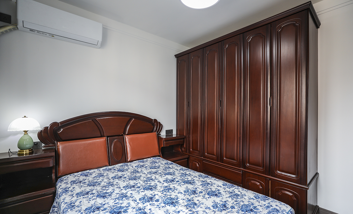 次臥室不做多余的修飾，白墻搭配深色實木家具，厚重富有底蘊。