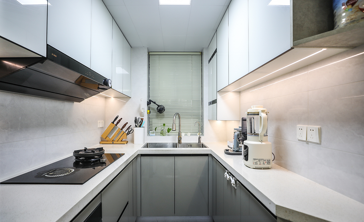 該套房子廚房空間很大，U型三面櫥柜，極大的滿足了客戶的操作需求，顏色簡(jiǎn)潔明快，材質(zhì)要干凈和好打理，白色的吊頂和米色的櫥柜相呼應(yīng)，石英石臺(tái)面經(jīng)久耐用，各種廚房電器全部配齊，滿足主人制作各種美食的需求。