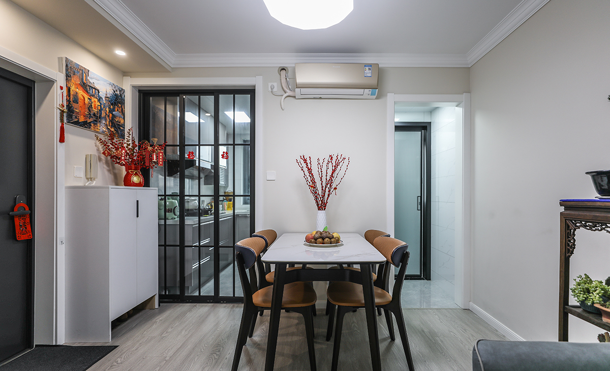 餐廳空間比較方正，但空間感略顯局促，靠墻做一排半高鞋柜，既實用、又有裝飾功能，通體白色鞋柜與淺色墻面相呼應，巖板餐桌把用餐氛圍調和的很溫暖，淺灰色地板很干凈，色彩和造型上都簡潔大氣。