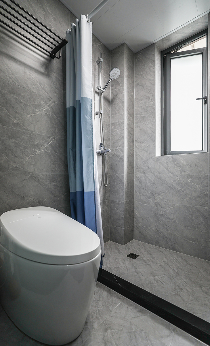 主衛空間并不大，淋浴區以浴簾代替隔斷，智能馬桶，墻地一體磚、白色吊頂，鈦合金移門，體現主人高檔次的生活品味和優雅的審美觀。