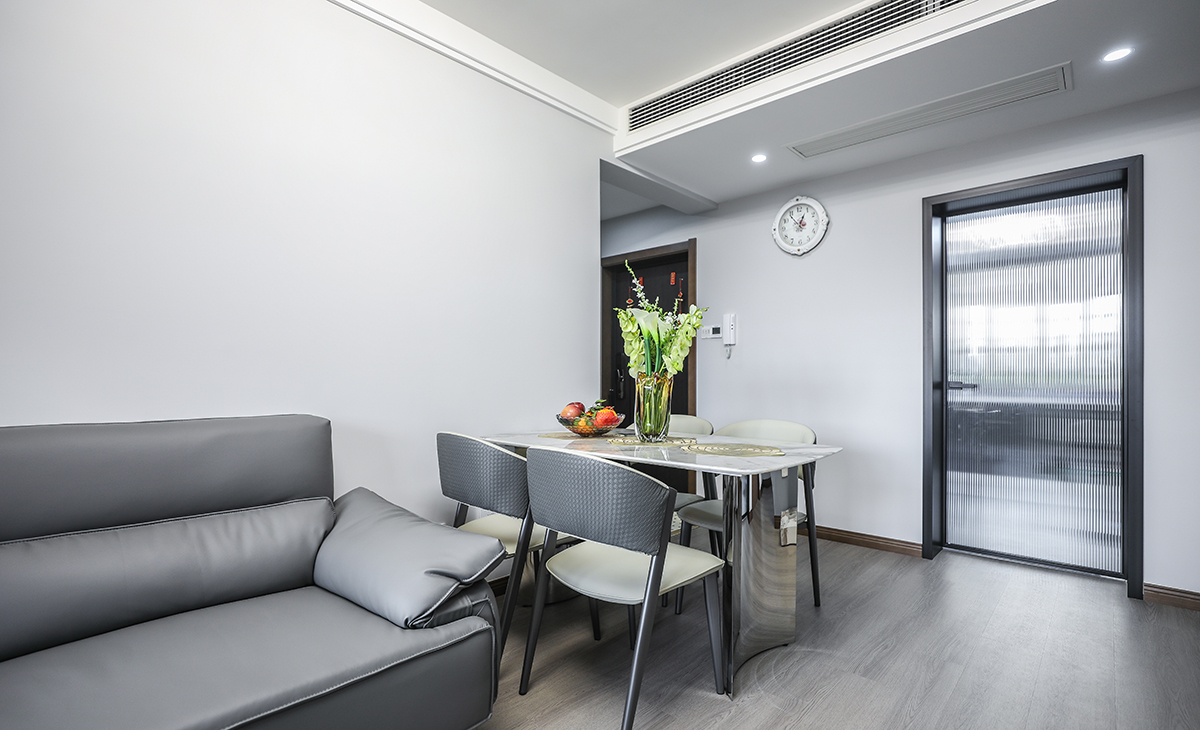 低調沈穩的空間中，擺置上現代風的簡約餐桌。當室外天光透入，與光潔的桌面和透明感的瓶罐飾品交映，光影舞動之間，形塑出一股柔美婉約的質感。