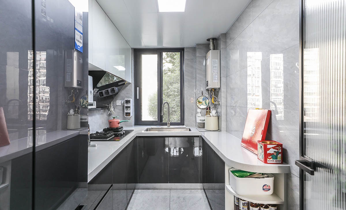 此廚房室U型設計，水槽、切菜，烹飪、等都沿著一條直線或直角排列，這樣的布局既方便了操作，也節省了空間。色調以黑白為主，線條簡潔，沒有過多的裝飾，看起來非常干凈利落這樣的布局既實用又美觀。