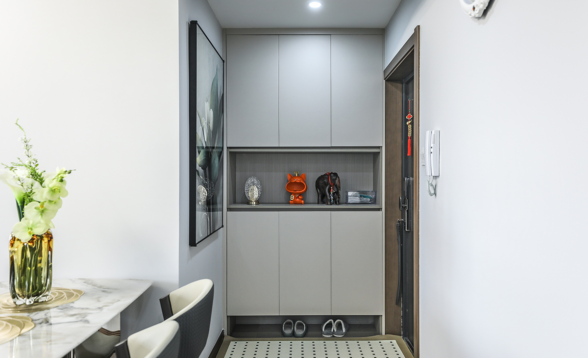 關柜功能上在接待客人、換衣、換鞋和放包的功能等，還具有延伸空間的效果。此外，它也可以打造成小平臺，放置小物品如鑰匙，從而增加居家裝飾的趣味性。裝飾物和紅色玩偶放在柜子的中空處，這種布局方式不僅突出了紅色元素，還增加了空間的藝術感和層次感，同時進門之后是一堵墻，墻面上放置一幅裝飾畫，顏色漂亮獨特。而且。特別在家人或朋友來訪時，能有效解決視覺干擾和心理安全問題，使出入過程更加有序。