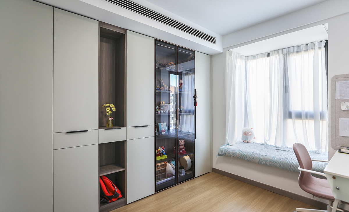 朝北次臥是書房，整面墻做書柜和物物柜，儲物柜式樣很豐富，有開放的、有封閉的，有半透明的玻璃柜，大飄窗、明軌紗簾，營造了活潑，天真、舒適的氛圍。