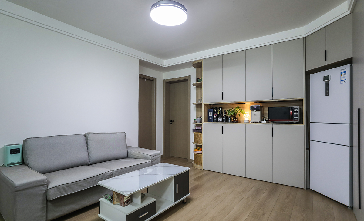 沙發背景刷純白色的涂料，干凈，整潔，清爽。色調上墻面涂料和沙發的深灰色，深淺搭配的錯落有致，既溫馨又簡潔。