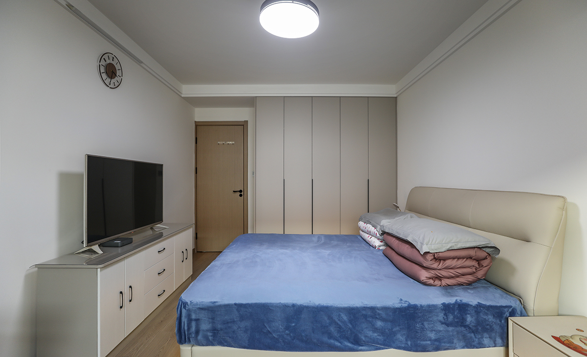 主臥原實木地板，所以床選擇的是暖灰色，衣柜門板也是暖灰色，這樣和地板進行搭配，非常的和諧、整體。頂面圓型吊扇燈，實現方中有圓，圓中有方，造型以簡潔平板為主，方便打理，體現了簡約風格的簡潔、隨意，不拘一格。