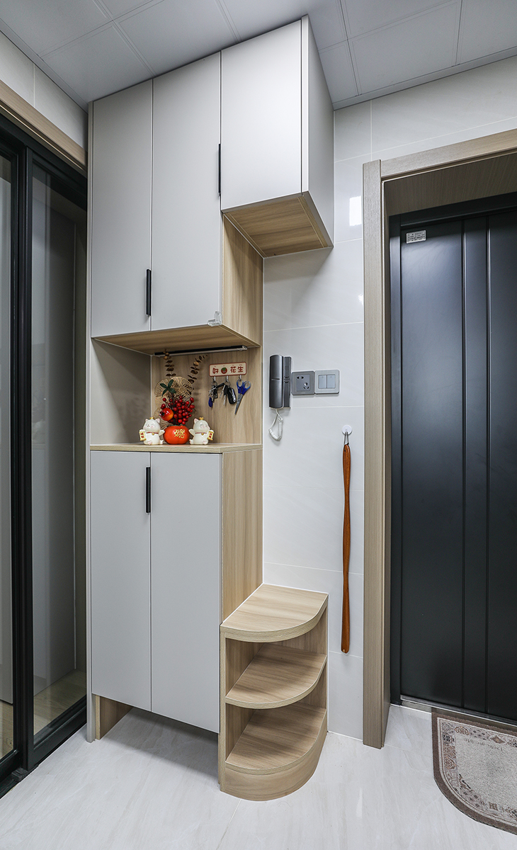進門鞋柜做成上下柜，中間落空，平時汽車鑰匙，小包都可以擺放。邊上做一個離地45公分高的下柜，再也不用站著換鞋。還做了倒圓處理，節約了空間，還防止進出磕碰。