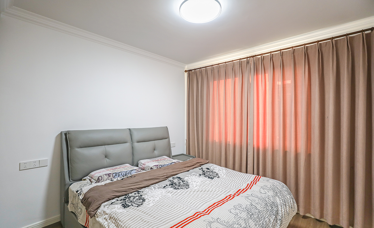 主臥增加儲藏，既美觀又實用，顏色上深淺搭配地錯落有致，橡木色地板，墻面暖白色干凈清爽，頂面白色乳膠漆，輕巧時尚的吸頂燈，空間很溫馨和諧。