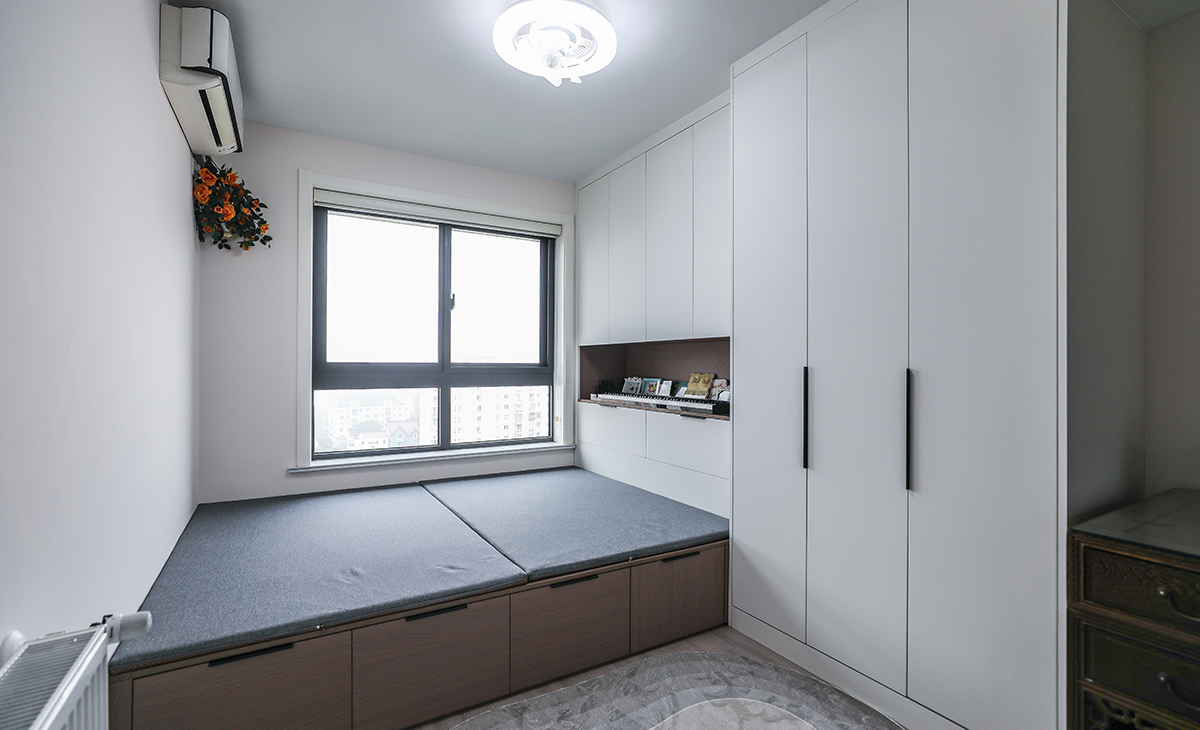 小次臥做了榻榻米和寫字臺，平時做書房用，榻榻米供外孫住，造型上以方正為主，色彩上以淺色為主，榻榻米下面和衣柜解決主人的收納，1.5米長的寫字臺可以解決主人的辦公需求。