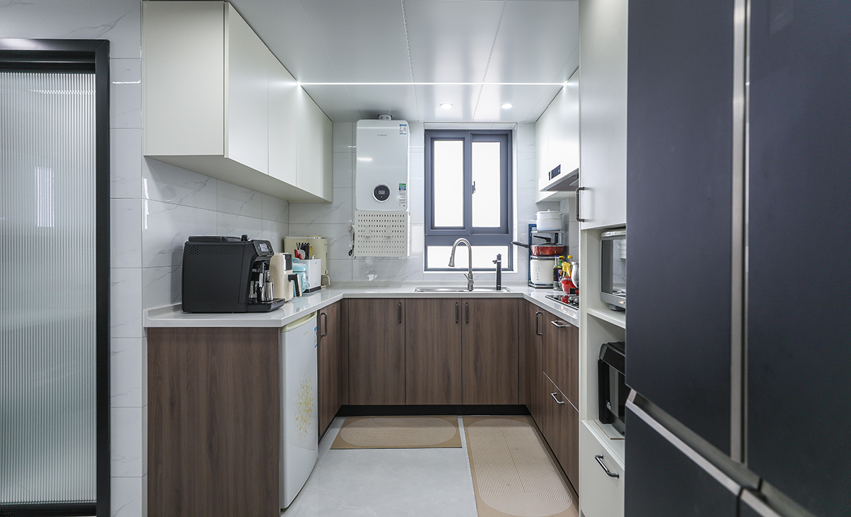 該套房子廚房空間很大，U型三面櫥柜，另外冰箱邊上做了到頂的電器高柜，顏色簡潔明快，材質要干凈和好打理，白色的吊頂和米色的吊柜櫥柜相呼應，石英石臺面經久耐用，各種廚房電器全部配齊，滿足主人制作各種美食的需求。