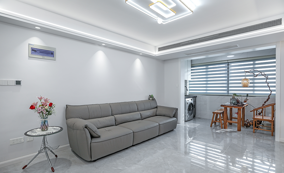 沙發(fā)背景刷米灰色涂料，頂面線型燈與射燈的搭配給沙發(fā)背景額外增加一絲風(fēng)采，沙發(fā)用深色，深淺搭配的錯(cuò)落有致，既溫馨又簡(jiǎn)潔。