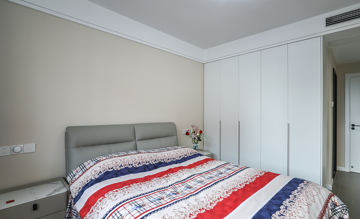 主臥地面采用的是實(shí)木復(fù)合地板淺灰色，與床及床頭柜搭配為一體，更衣柜采用一門(mén)到頂做法，預(yù)留暗裝拉手造型以簡(jiǎn)潔平板為主，方便打理，頂面為雙眼皮吊頂，內(nèi)嵌中央空調(diào)，在每個(gè)角度我們臥室都是一個(gè)整潔、簡(jiǎn)約、也不失優(yōu)雅的一個(gè)空間。