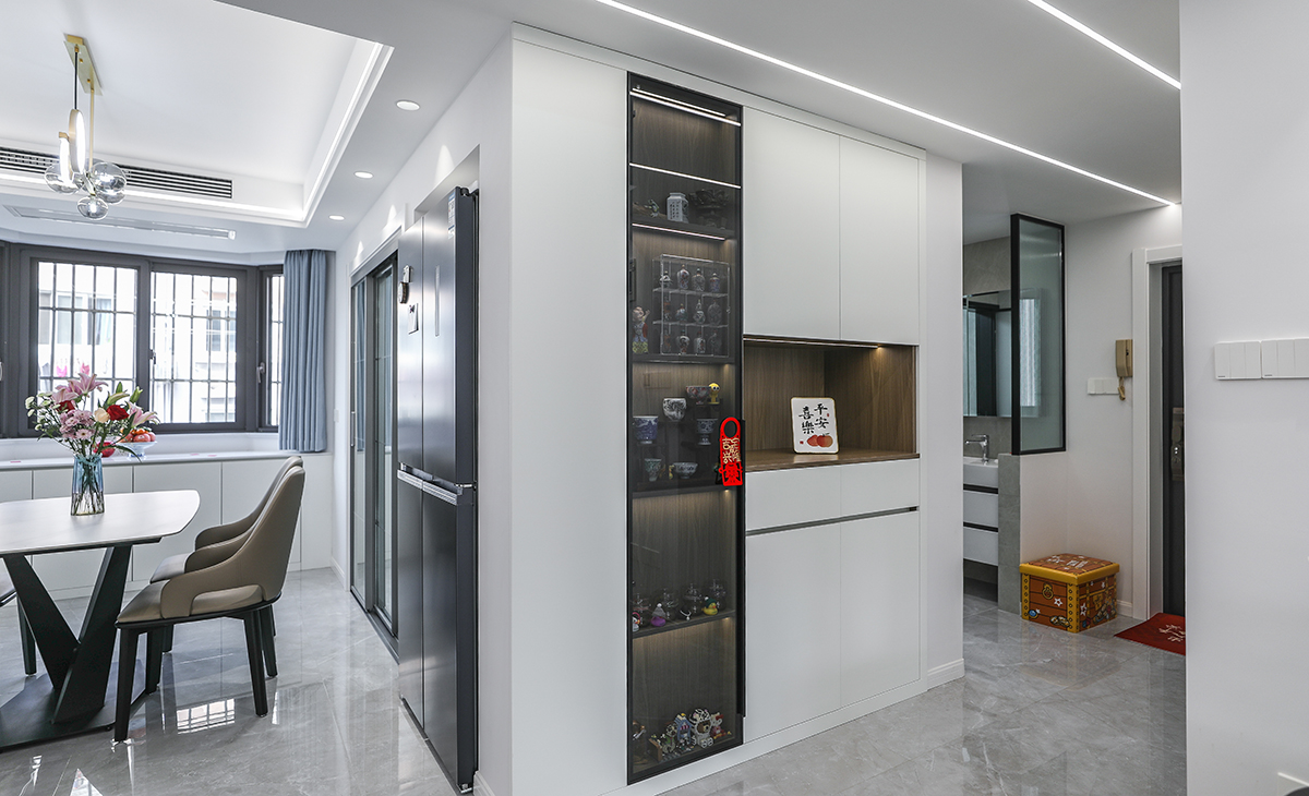 本套房子的走道儲(chǔ)物柜設(shè)計(jì)也是一大亮點(diǎn)，既實(shí)用，又有裝飾性，雙門(mén)儲(chǔ)物柜，留一門(mén)做玻璃門(mén)板，展示主人收藏的藝術(shù)品，門(mén)板采用平板一門(mén)到頂，和臥室門(mén)顏色相統(tǒng)一，給人感覺(jué)不僅雅致而且有韻味。