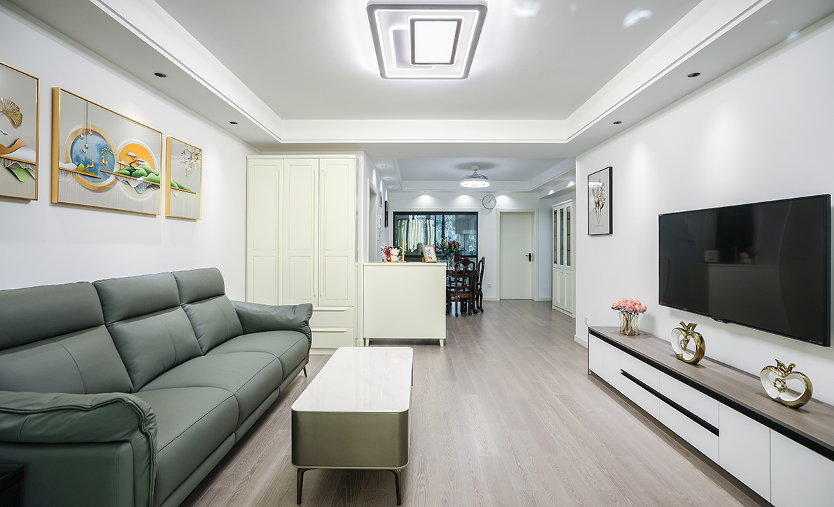  客廳面積不大，但經(jīng)過設(shè)計師的手筆，讓空間緊湊不擁擠，電視墻落地電視柜，柜子色系和沙發(fā)相互配合，明暗有神，深灰色皮質(zhì)沙發(fā)立刻檔次提高很多。吊頂造型上采用雙眼皮圍邊吊頂，讓造型簡介配合筒燈打造氛圍感。地面采用棕色地板。造型和色調(diào)上無不給人以簡潔、溫馨、時尚的感覺。