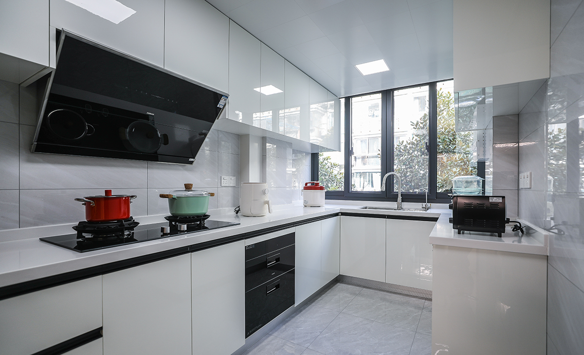 該套房子廚房空間較大，U型三面櫥柜，采用高光pet門板，顏色簡潔明快，材質(zhì)干凈和好打理，白色的吊頂和白色的上、下櫥柜相呼應(yīng)，石英石臺面干凈、好打理，各種廚房電器全部配齊，滿足主人制作各種美食的需求。